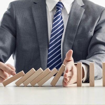 businessman-suit-protecting-wooden-blocks-from-falling-domino-effect_181624-47114